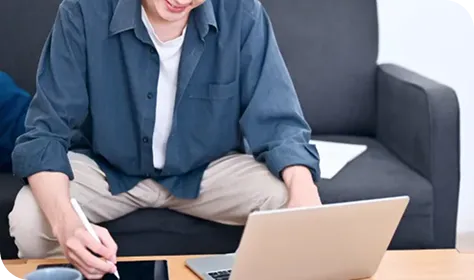 自宅でノートパソコンを使いながら作業する男性